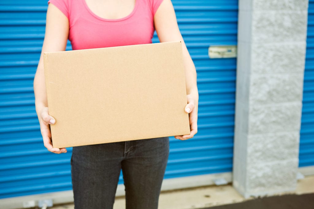 woman holds box in front of self storage unit